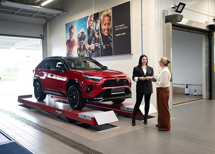 Klientka i konsultantka obok Toyoty na podnośniku